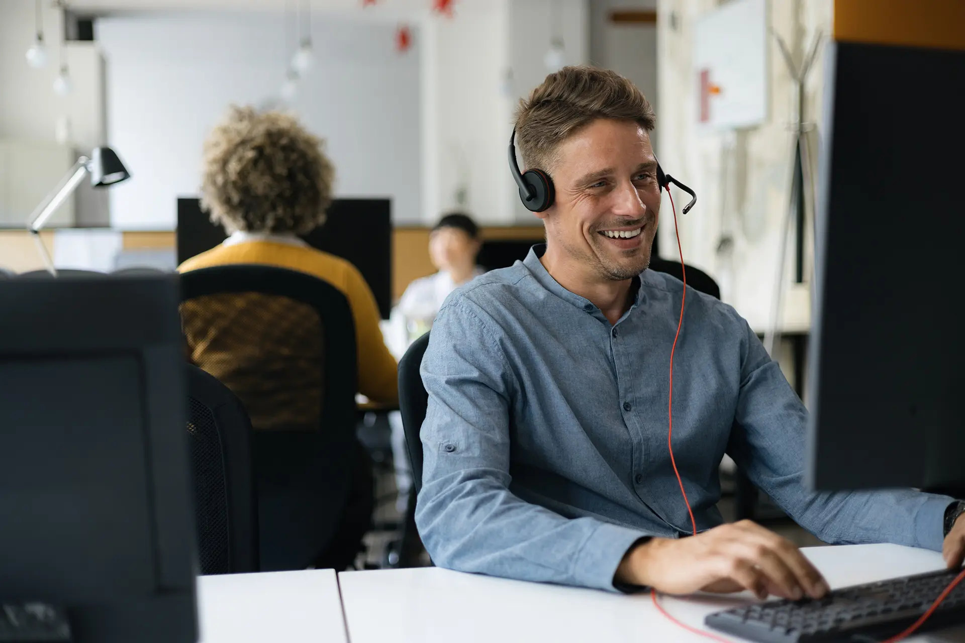 Man smiling wearing a headset providing friendly chat support.